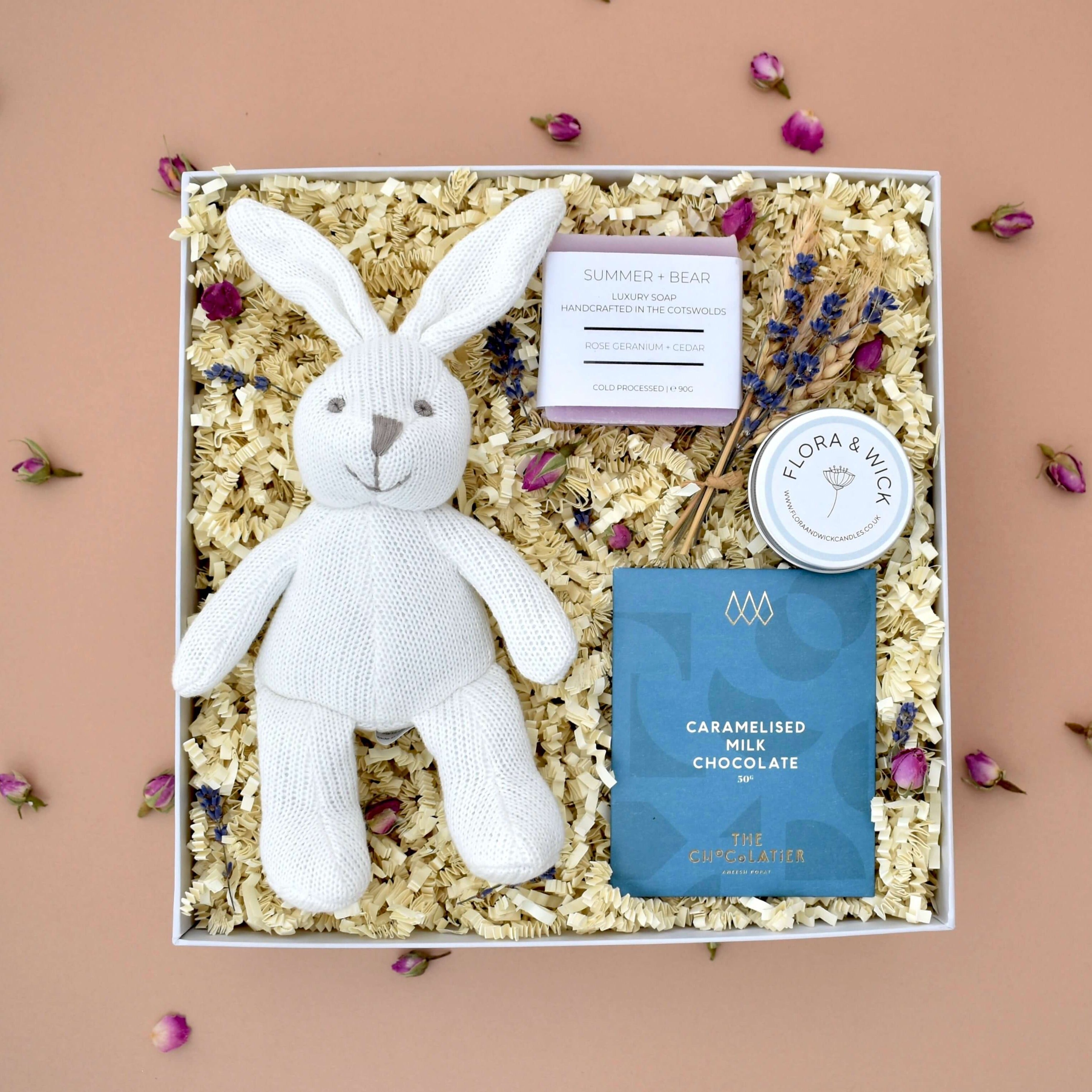 new mum and baby pamper luxury gift box. With organic baby bunny rattle, handmade rose geranium and cedar bar of soap, orchard blossom scented handmade tin candle, bar of caramelised milk chocolate, decorative keepsake floral arrangement.